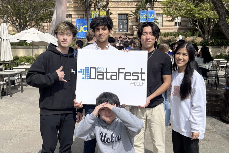 A photo of Anish Dulla on the UCLA campus with fellow undergraduates holding a sign promoting the Data Fest event