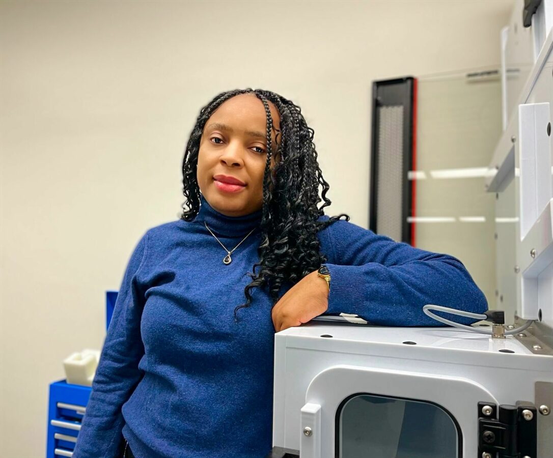 Professor Alvine Kamaha standing in front of instrumentation in her laboratory