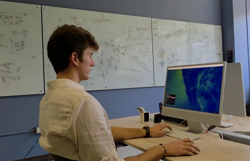 A student in the program looks analyzes weather models on a computer