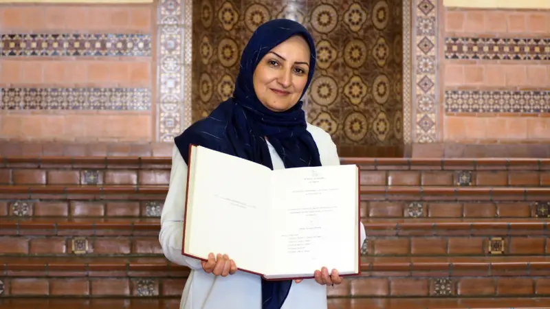 Azadeh Baniasad holding her uncle’s dissertation in Powell Library